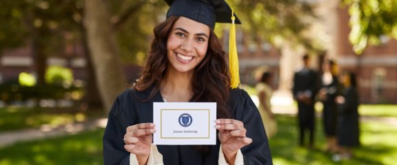 A graduating student holding up their graduation announcement.