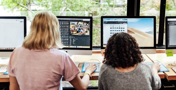Two people at desktop computers looking at images.